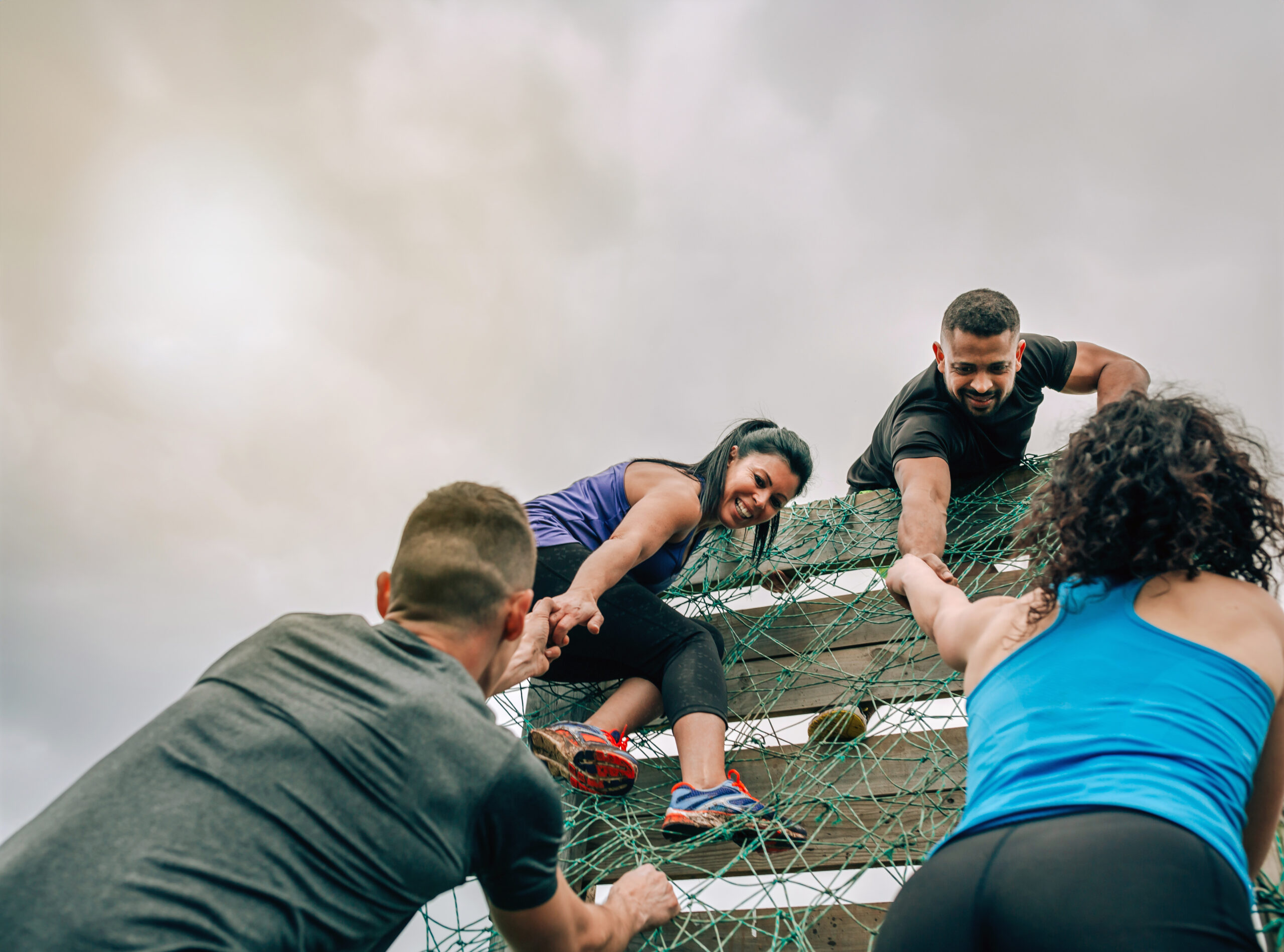 Allyship shown by Group of participants in an obstacle course climbing a net